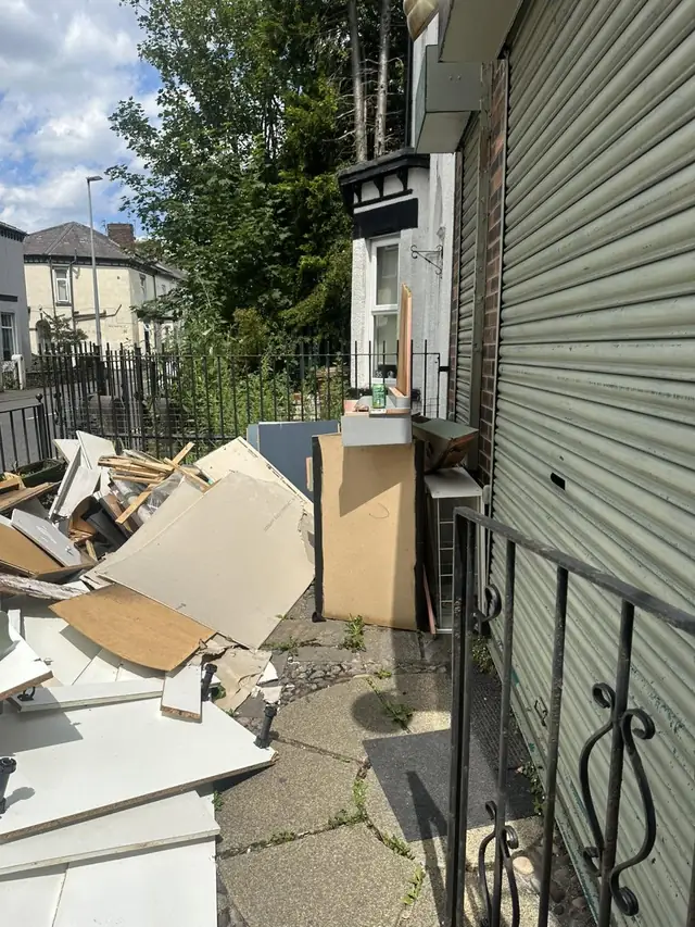 Bulky waste and broken furniture piled up in a front garden in Salford, before collection